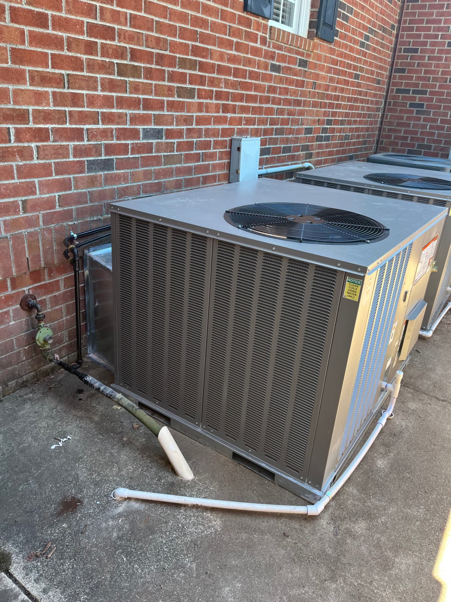 Packaged HVAC unit set on a concrete pad with gas piping and condensate lines connected