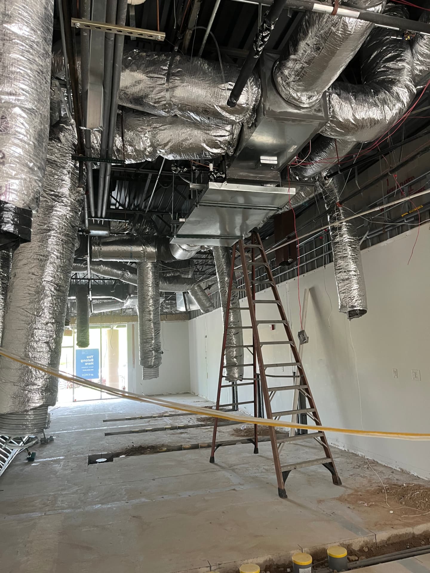 Insulated HVAC ductwork and trunk lines installed overhead during a build-out by Outdoor Breeze
